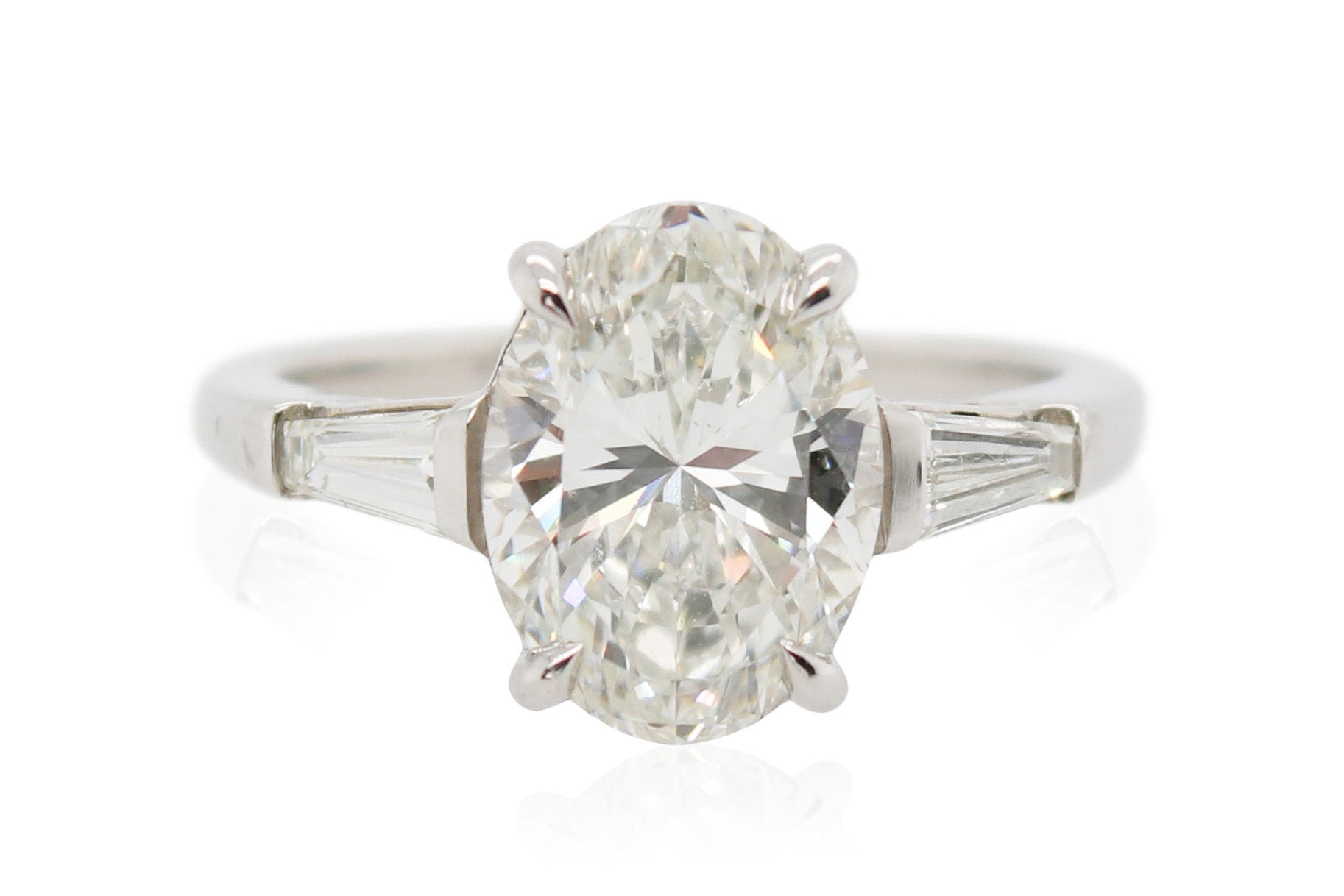 A platinum ring with an oval center diamond and tapered baguette side stones.