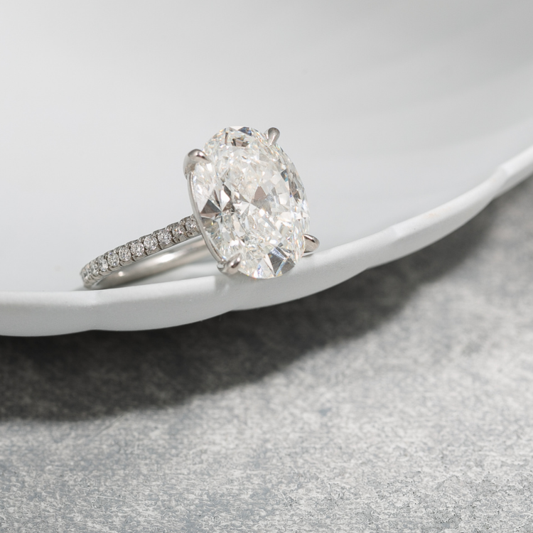 Large oval diamond ring on the edge of a white dish