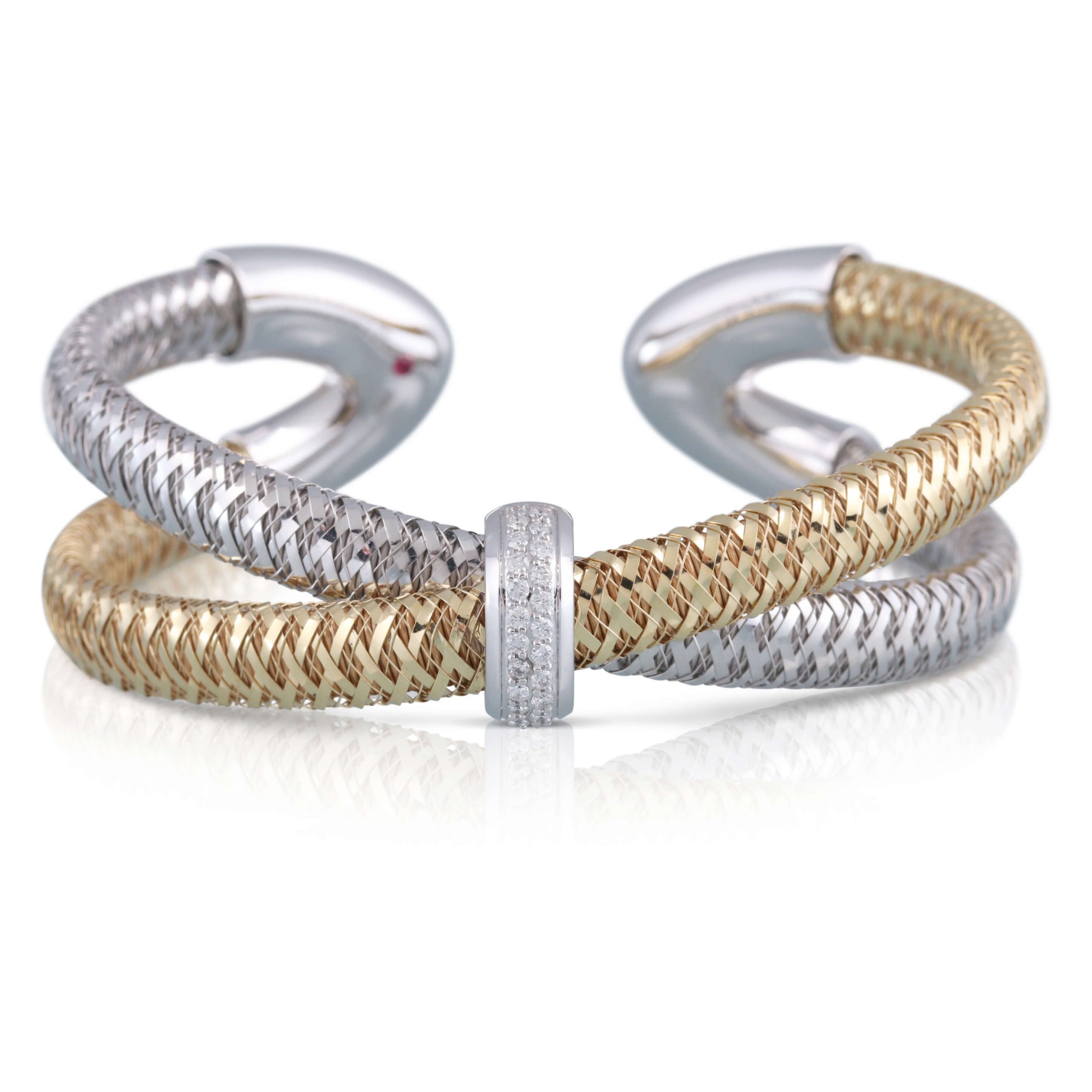 White and yellow gold cuff bracelet. Woven strands of white gold and yellow gold crossover and meet at a high polish white gold V on either end of the cuff. The center features a white gold station with diamonds.