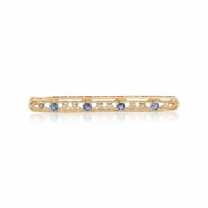 This bar pin is crafted from 14k yellow gold and features sapphires and seed pearls.