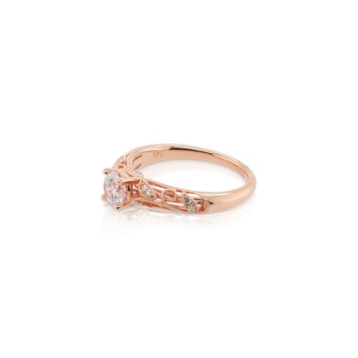 This diamond engagement ring mounting by Sylvie is crafted from 14k rose gold and features 0.12 total carats of diamonds scatered throughout the elegant filigree design. The center diamond is chosen separately.