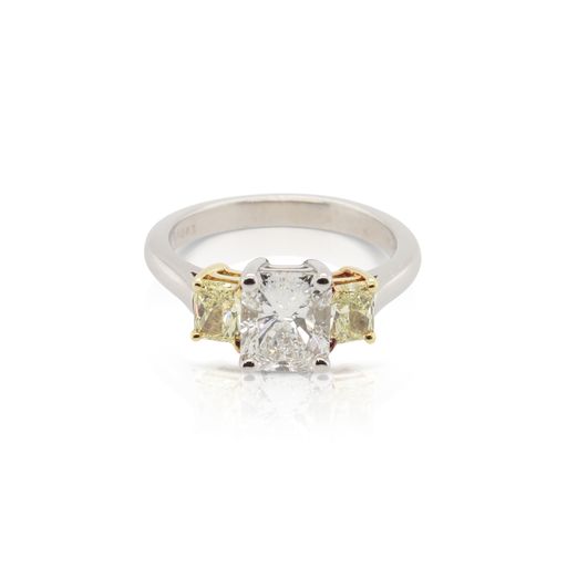 This three stone ring is crafted from platinum and 18k yellow gold and features a 1.51 carat radiant diamond and 0.69 total carats of fancy yellow radiant side diamonds.