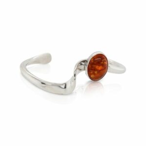 This cuff bracelet is crafted from sterling silver and features an oval cabochon amber.