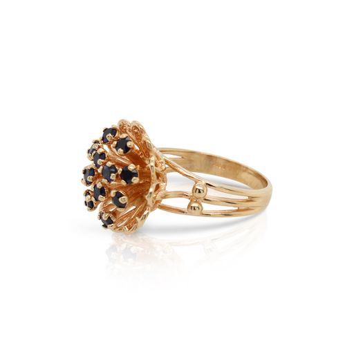 This floral ring is crafted from 14k yellow gold and features sapphires.