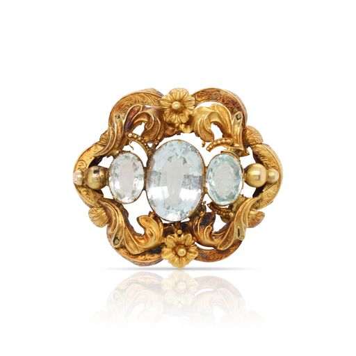 This brooch is crafted from 18k yellow gold and features 3 aquamarines and a repousse engraving.