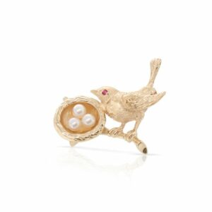 This bird brooch is crafted from 14k yellow gold and features 3 small pearls as the eggs.