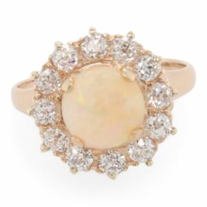 This ring is crafted from 14k yellow gold and features a round opal and 0.66 total carats of diamonds around the halo.
