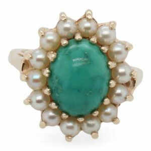 This ring is crafted from 14k yellow gold and features an oval turquoise and pearls around the halo.
