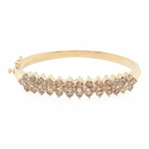 This bangle bracelet is crafted from 14k yellow gold and features 5.60 total carats of cognac diamonds.